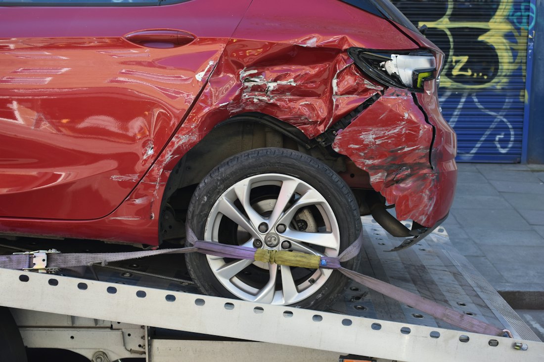 Damaged car strapped onto a flatbed tow truck